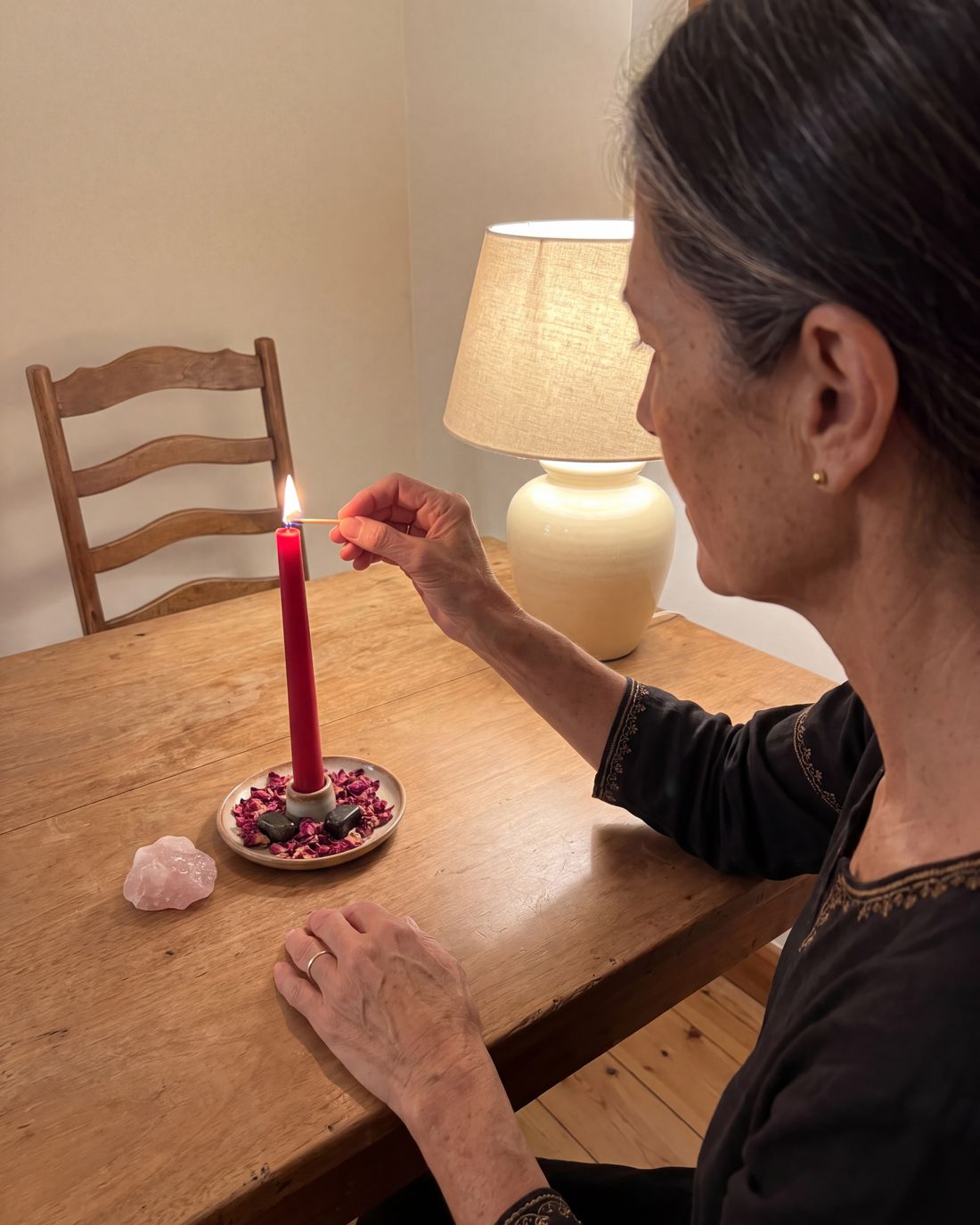 Amara lighting a red candle at her dining table in the evening