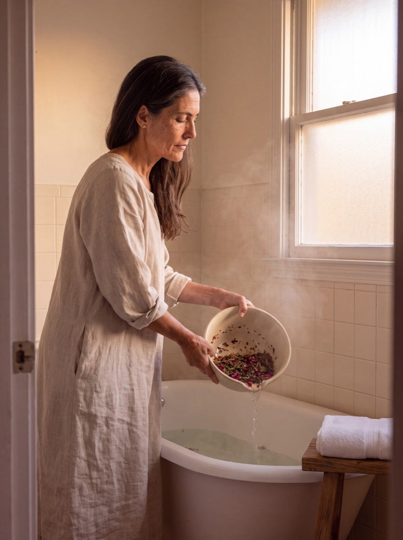Amara pouring steeped herbs and rose petals into a claw-foot tub